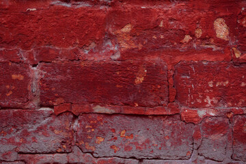 A fragment of a red brick wall with pronounced texture. Natural age defects in the form of cracks and abrasions. Rough surface with traces of dried paint.