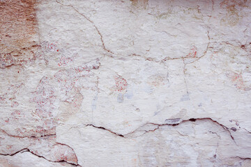 Grey concrete wall with natural defects. Fragment of the cement surface with natural texture. Natural cracked plaster on a light wall. Textured background for integration into the design.