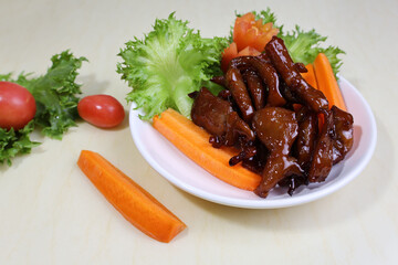 Sliced ​​pork fried in juicy sauce Place a plate with greens, tomatoes and carrots on a cream-colored marble table.

