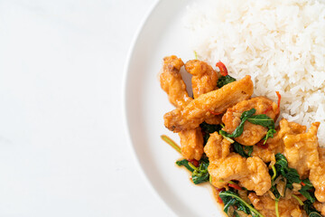 stir-fried fried fish with basil and chili in thai style topped on rice