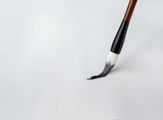 Chinese art brush ink on white paper. The concept of tools for painting, teaching drawing. Macro photo.