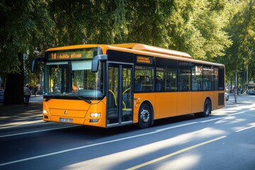 Fototapeta premium An orange city bus on a tree-lined street, ready for passengers.