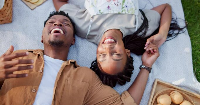 Above, black couple and laugh with rest on picnic for romantic date, trust and food basket of anniversary. Smile, people and funny joke of comic affection, relationship bonding and commitment outdoor