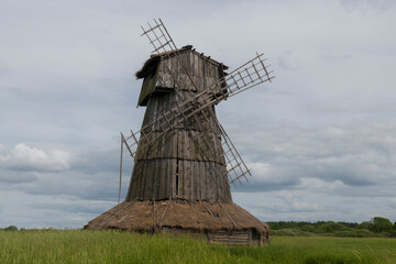 An old wooden mill in a field on a cloudy June day. Loskovitsy tract (Loskovskoye). Pskov region, Russia