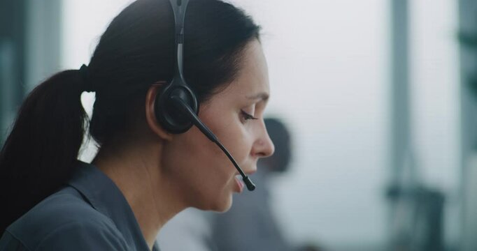 Female helpdesk specialist working in modern call center office: Close up portrait of Caucasian hotline operator using headset to talk with client, providing online technical support for customer. - Powered by Adobe