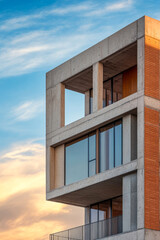 Modern architectural design of a concrete building against a vibrant sunset sky
