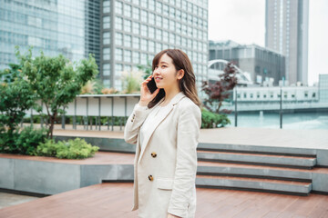 スマホを使うビジネスウーマン（通話・笑顔）
