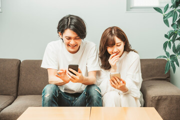 部屋でスマホを使う男女
