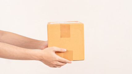 Hand holding cardboard box on empty background. Concept for transportation, online shopping, celebration and gift giving on special day.