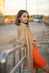 Portrait of a beautiful young girl in an orange dress in an urban environment.