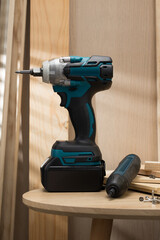 Cordless electric drill and screwdriver on a wooden table.