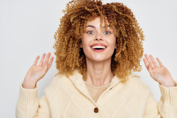 Happy woman with curly hair smiling enthusiastically against a light background with neutral tones,...