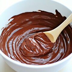Melted chocolate in a white bowl with a wooden spoon.