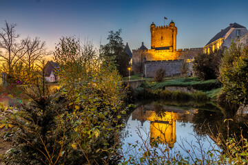 Burg Bad Bentheim beleuchtet spiegelt sich bei Sonnenuntergang im Schlossteich.