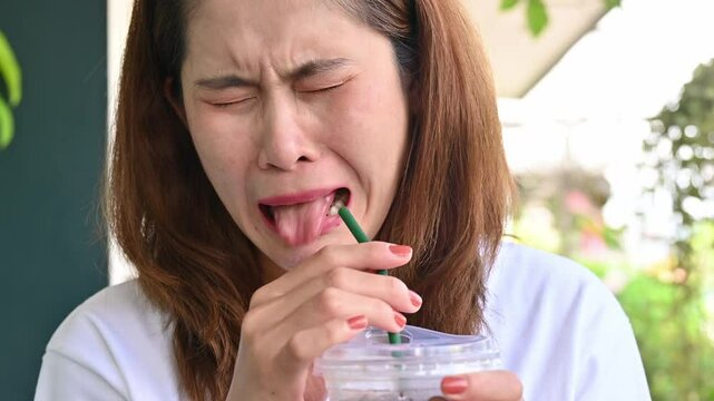 Facial expression of young Asian woman after drinking strong coffee. Strong coffee may be used to describe bitter or highly caffeinated coffee.