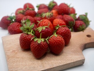 Red strawberries on wooden cutting board isolated on a white background. Sweet strawberry
