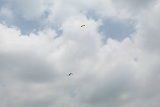 Two parachutes of paragliders with cloudy sky background