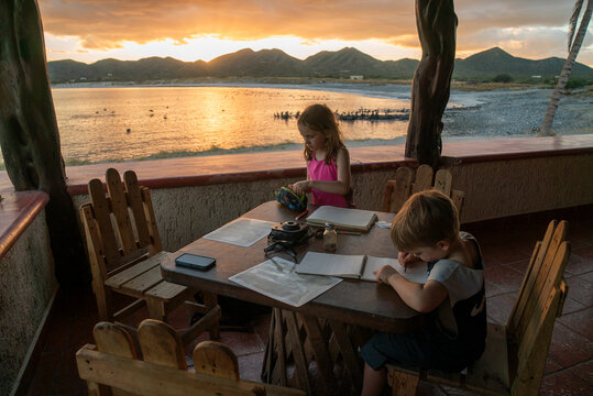 A boy and girl color at a cafe table by the beach