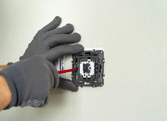 Electrician hands install electric light switch using screwdriver. Replacing electrical switch....
