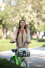 A woman is riding a green bike with a basket on the front