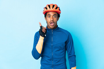 Young cyclist man with braids over isolated background intending to realizes the solution while lifting a finger up