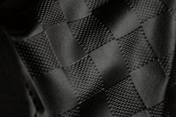 Black checkered faux leather with creases as background, black background