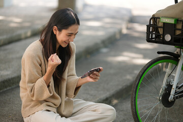 A woman is sitting on the ground and holding a cell phone