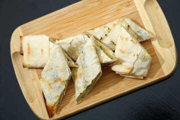 Lavash with baked cheese. Lavash with baked cheese on a wooden board. Lavash with cheese.