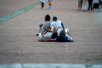 Obraz premium A couple laying on pavement and using smartphones