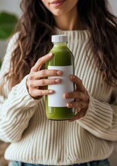 Woman holding a bottle of green detox juice drink refreshment midsection.