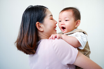 The mother is holding a baby and smiling.