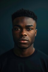 Portrait of a young man with sharp features set against a deep navy backdrop. intense lighting accentuates his confident expression, ideal for professional projects needing a bold