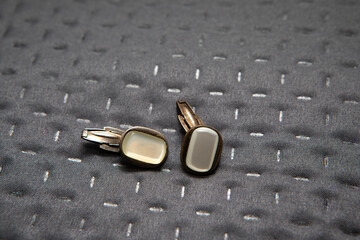 Elegant cufflinks resting on quilted gray fabric