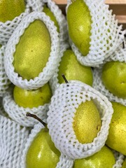 Lot of ripe fresh pears in net foam are sold at supermarket.
Pears with net foam in grocery store.