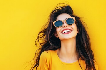 cheerful young woman in stylish sunglasses smiles brightly against a vibrant yellow background, capturing a moment of joy and carefree beauty.