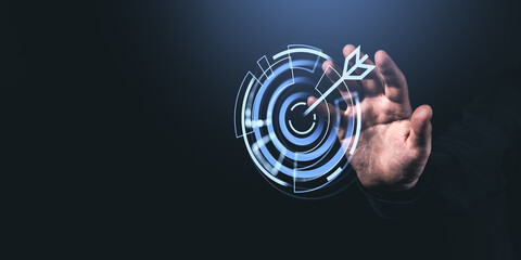 Man's hand touching digital target with arrow icon on dark background.