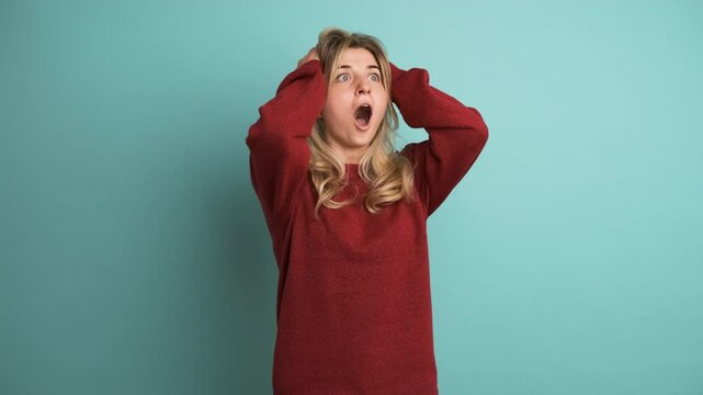 Stunned young woman with opened mouth in blue studio