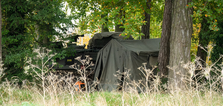 an amry Bulldog FV432 tank and tent amongst woodland cover