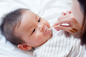 A baby or toddler is brushing his teeth and smiling.