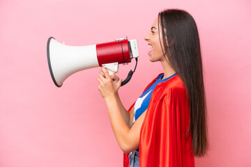 Naklejka premium Super Hero Caucasian woman isolated on pink background shouting through a megaphone