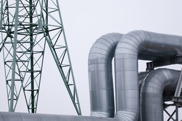 The photo shows a pipeline and a power line close-up against a gray sky