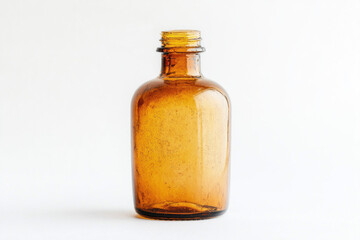 Brown glass bottle with brown cap on rustic wooden table, surrounded by fresh green leaves, bathed in soft natural light.