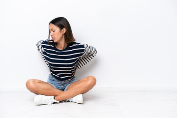 Young caucasian woman sitting on the floor isolated on white background suffering from backache for...