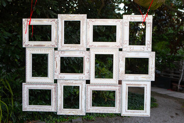 Empty white vintage frames hanging outdoors creating photo booth backdrop