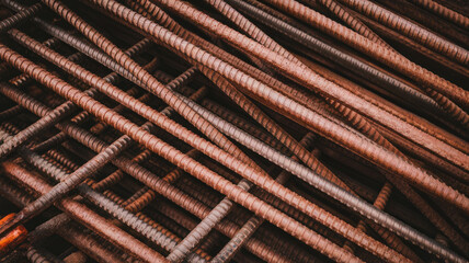A close-up view of intertwined steel rebar, showcasing various textures and colors, creating a raw industrial aesthetic with a focus on construction materials.