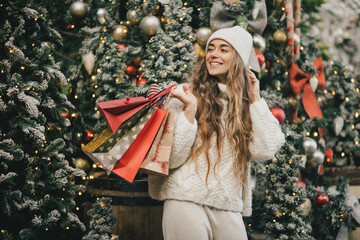 Young beautiful womam enjoying Christmas shopping on a decorated street.