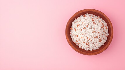 Closeup of white rice with red rice grains in a wooden bowl on a pink background.