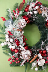 Christmas pine needle wreath with red decoration on green background
