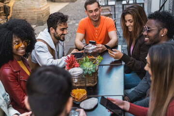 Diverse friends group using phones at social cafe terrace