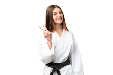 Teenager girl doing karate over isolated chroma key background smiling and showing victory sign © luismolinero
